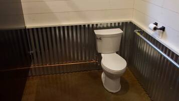A small bathroom with a toilet, a window, and a metal radiator.