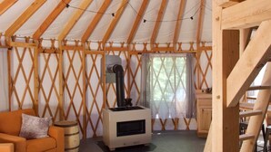 Un intérieur chaleureux d’une yourte en bois, avec un canapé, une table et un poêle à bois.