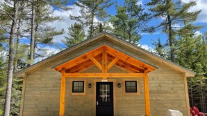 Una cabaña de madera con puerta negra, un porche con vigas de madera y un letrero que dice "Ranger Station".