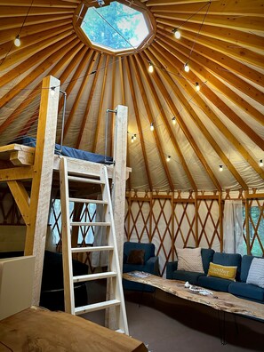 Indretning i en yurt med en træstige, en sofa og et bord.