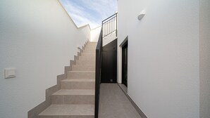 A narrow hallway with a staircase leading to a second floor. The walls are white, and there is a small window at the top of the stairs. - Villa Camilla Roda Golf (Roda)