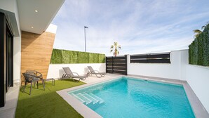A modern outdoor swimming pool with a wooden wall and a green hedge. - Villa Camilla Roda Golf (Roda)