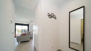 A modern interior with a hallway leading to a living area, a large mirror, and a geometric wall art piece. - Villa Camilla Roda Golf (Roda)