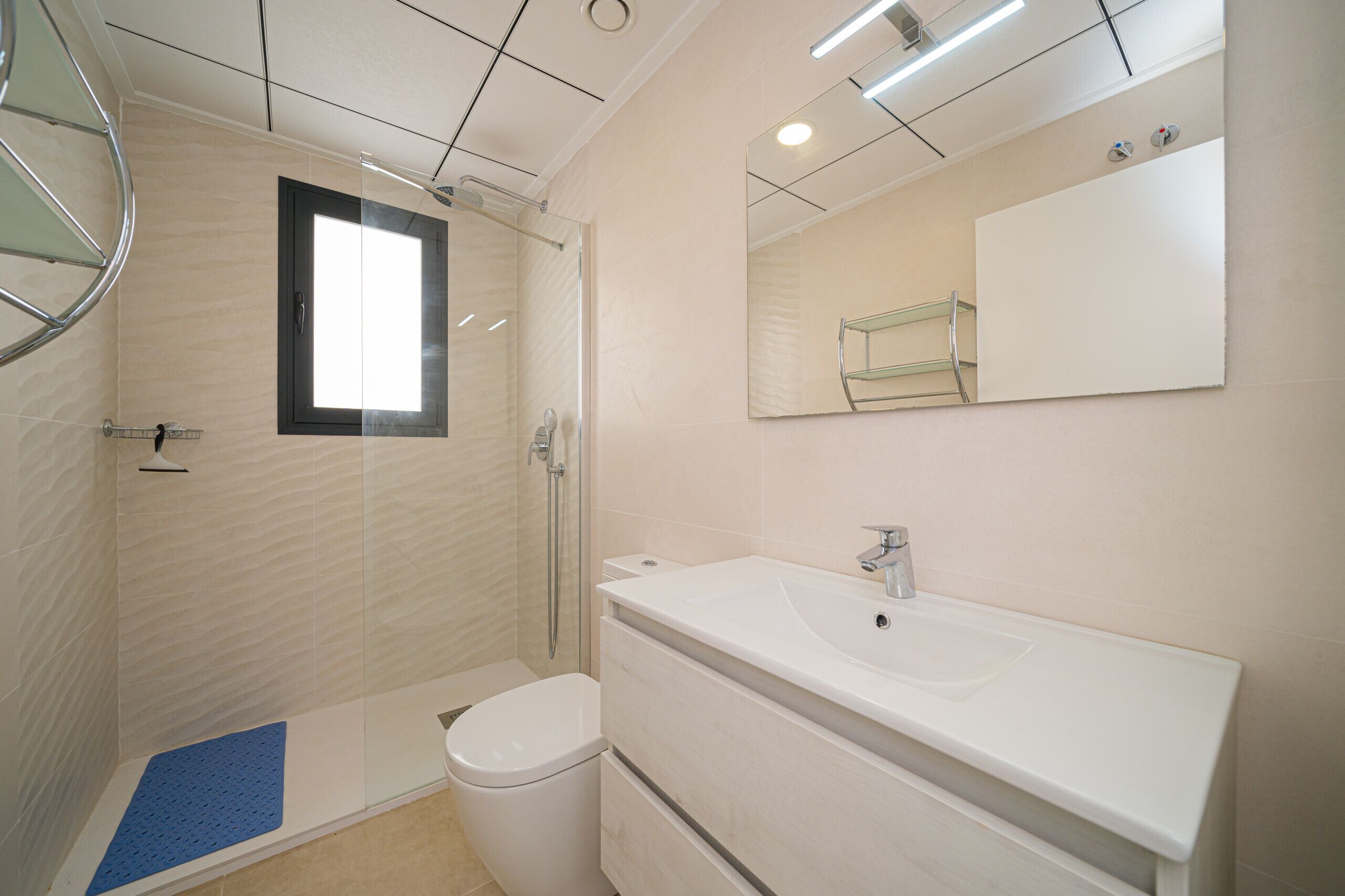 Une salle de bain moderne avec une douche à parois de verre, un lavabo blanc et un grand miroir.