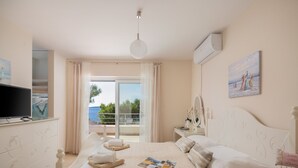 Un dormitorio con cama, mesita de noche, televisor y vistas al exterior.