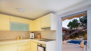 Una cocina moderna con armarios amarillos, una cafetera y vista a una piscina al aire libre.
