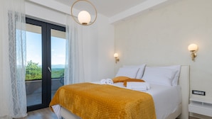 A bedroom with a bed, a view through a sliding door, and a wall-mounted light fixture. - Luxury Villa Phoenix with Pool (Labin)