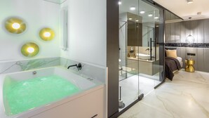 A modern bathroom with a large bathtub, glass shower enclosure, and a marble-tiled floor.