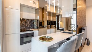 A modern kitchen with sleek cabinetry, a marble backsplash, and a central island with a glass top.