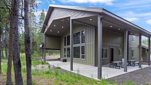 A modern building with a covered patio area, large windows, and outdoor seating. - Island Park Cabin with Private Dock on the Lake (Island Park)
