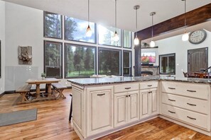 Une cuisine spacieuse, dotée de grandes fenêtres, d’un plancher en bois et d’un îlot central avec des placards.