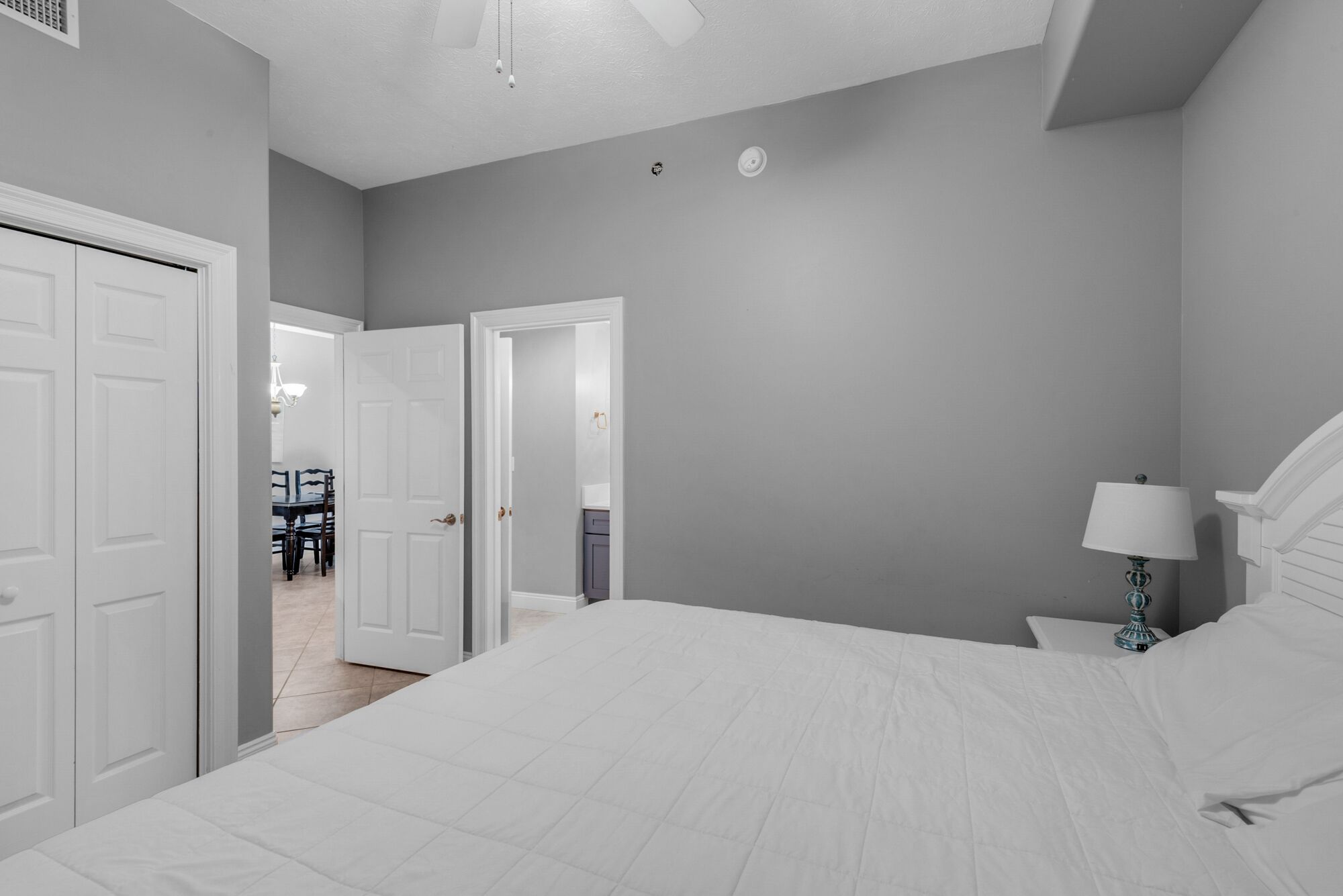 Une chambre à coucher comprenant un lit, une table de chevet, une lampe et une porte donnant sur un coin repas.