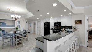 A modern kitchen with white cabinets, a granite countertop, and a black refrigerator. - Treasure Island 0104 (Panama City Beach)