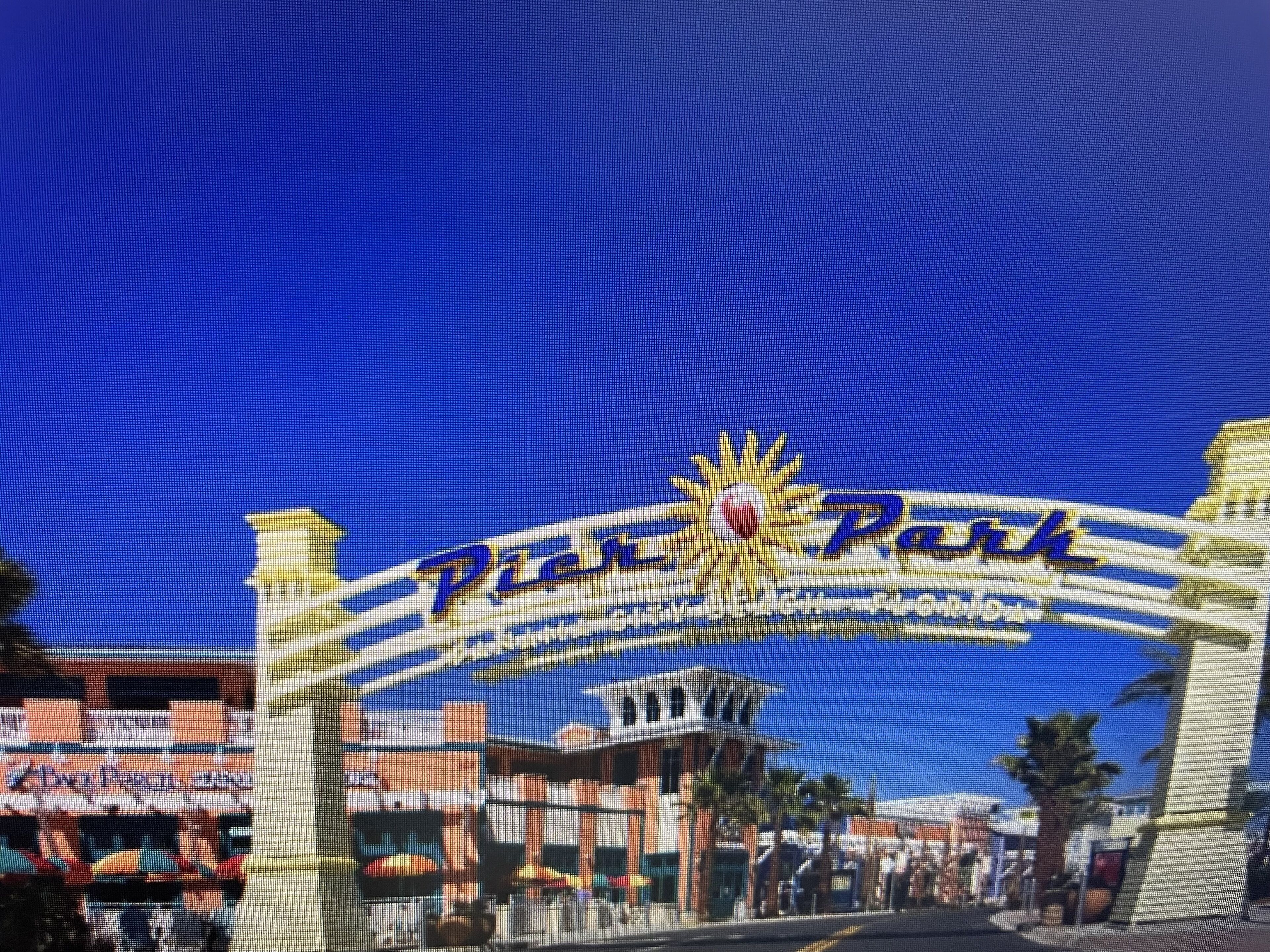 Een bord met 'Pier Park', met een zon en een palmboom logo, wat duidt op een themapark of een resortgebied.