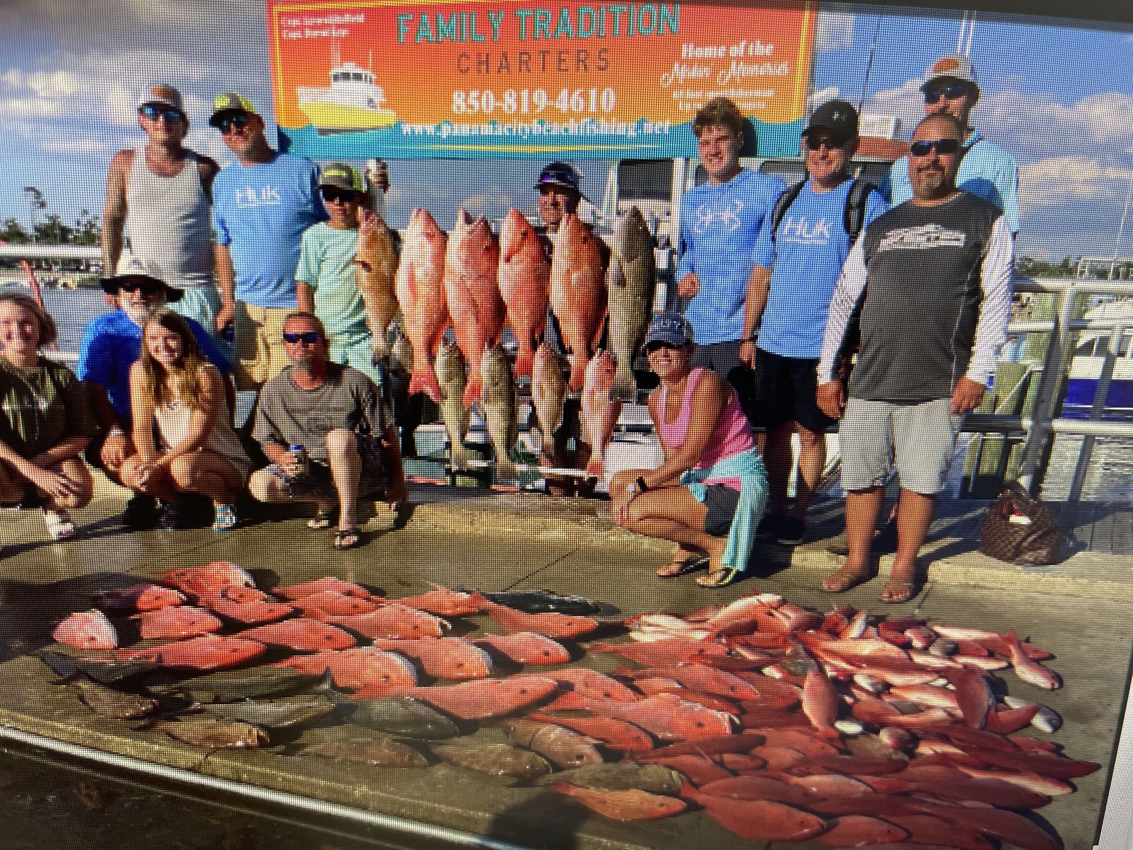 A group of people standing in front of a display of fish, with a banner in the background advertising a family tradition.