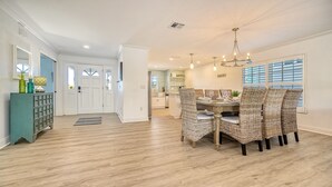 A dining area with wicker chairs, a wooden table, and a chandelier. - 🌴 Island Escape | Home on Siesta Key w/ Private Heated Pool & Ping Pong Table! (Siesta Key)
