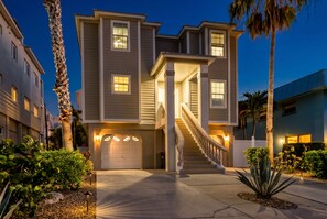 A multi-story residential building with a central staircase, a garage, and a well-lit entrance.