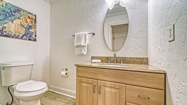 A bathroom with a toilet, sink, vanity, and a mirror.