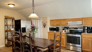 A modern kitchen with wooden cabinets, stainless steel appliances, and a dining area with a wooden table and chairs. - Spacious & Modern with Workspace - A+ Location!!! (Mooresville)