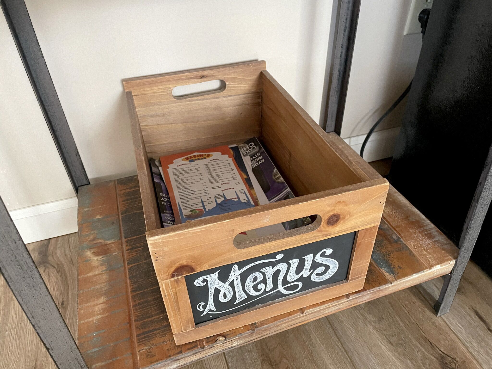 Una caja de madera con un cartel que dice 'Menús', conteniendo un folleto de menú.