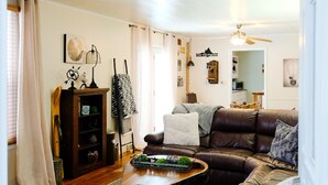 A living room with a brown leather sofa, a wooden coffee table, and a patterned rug. - The SISU Shack - 4BR Trailside Stay (Ironwood)