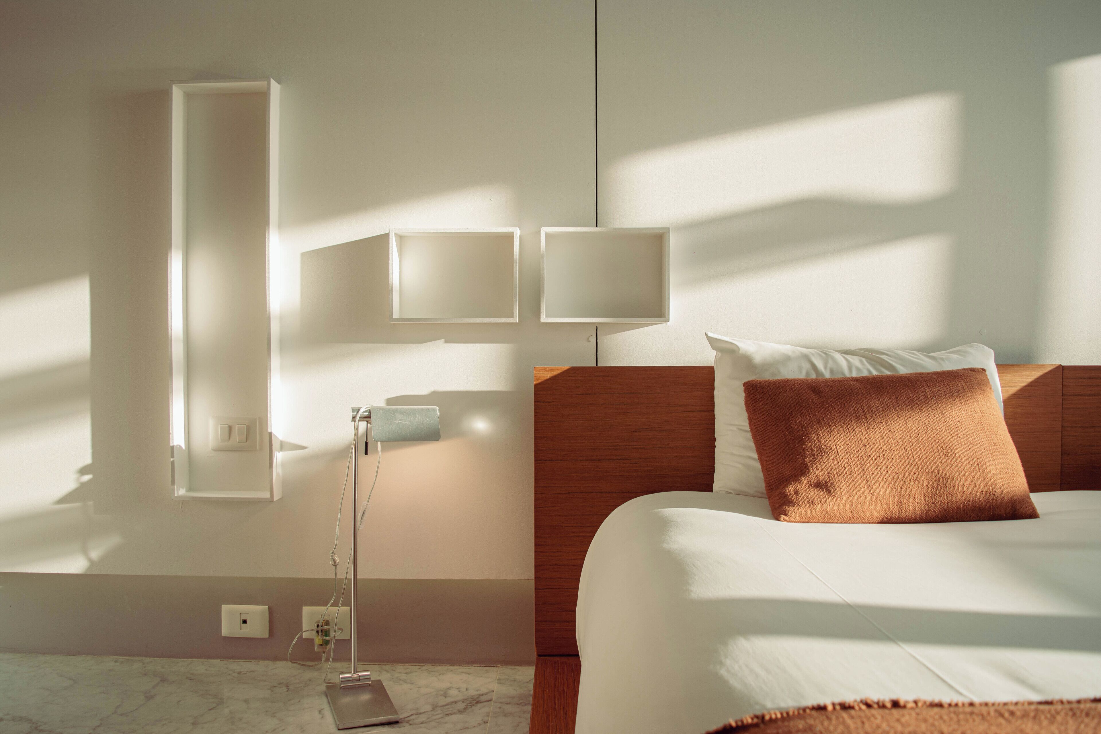Ein Hotelzimmer mit einem Bett, einem Nachttisch, einer Lampe und Wandleuchten.