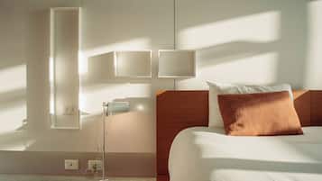 Ein Hotelzimmer mit einem Bett, einem Nachttisch, einer Lampe und Wandleuchten.