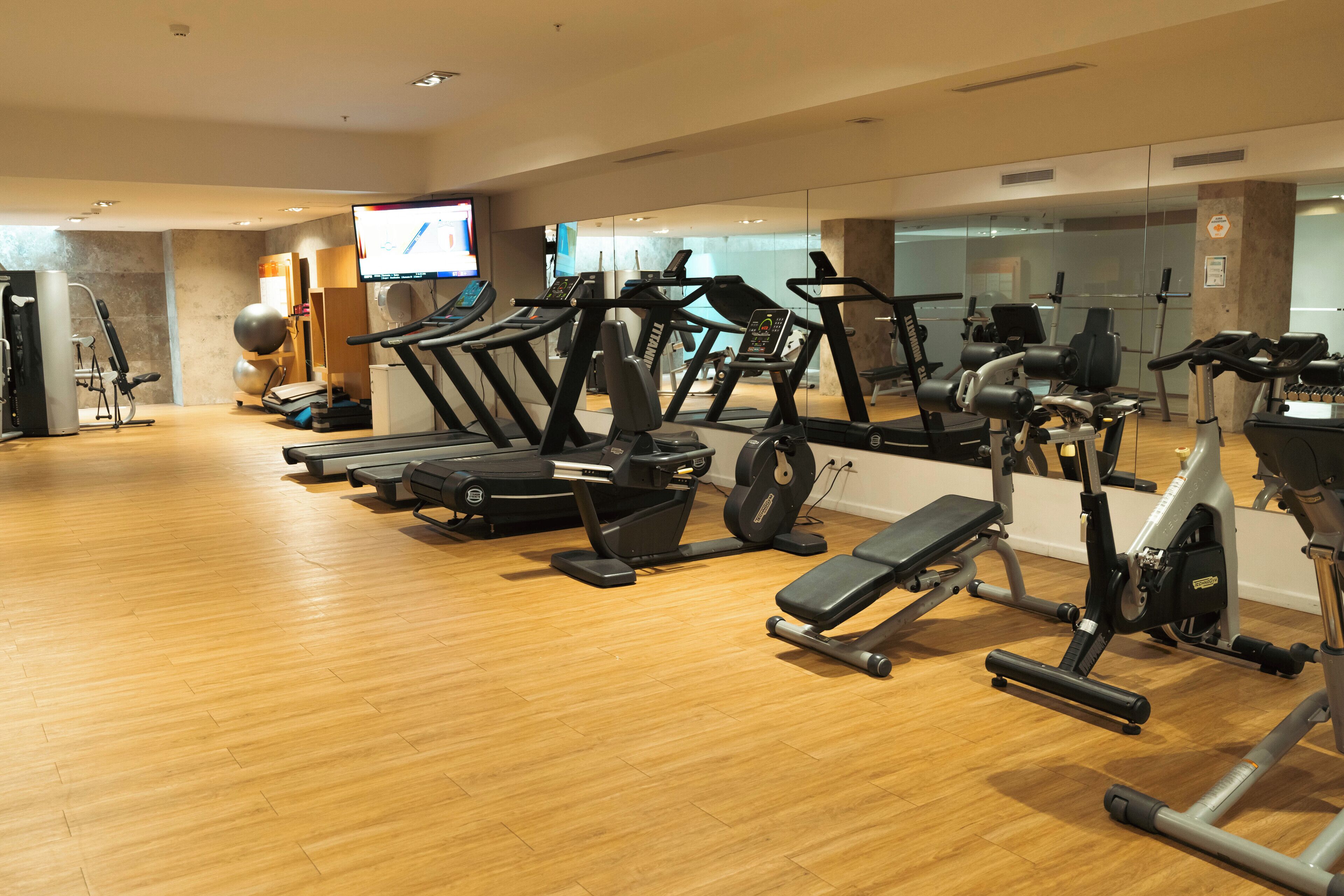 Un gimnasio con cintas de correr, elípticas y equipo de pesas.