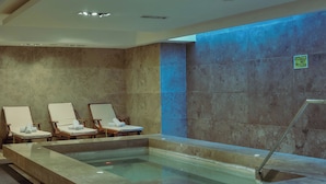 A spa area with a rectangular pool, three lounge chairs, and a caution sign on the wall. - Opta Coliving (Montevideo)