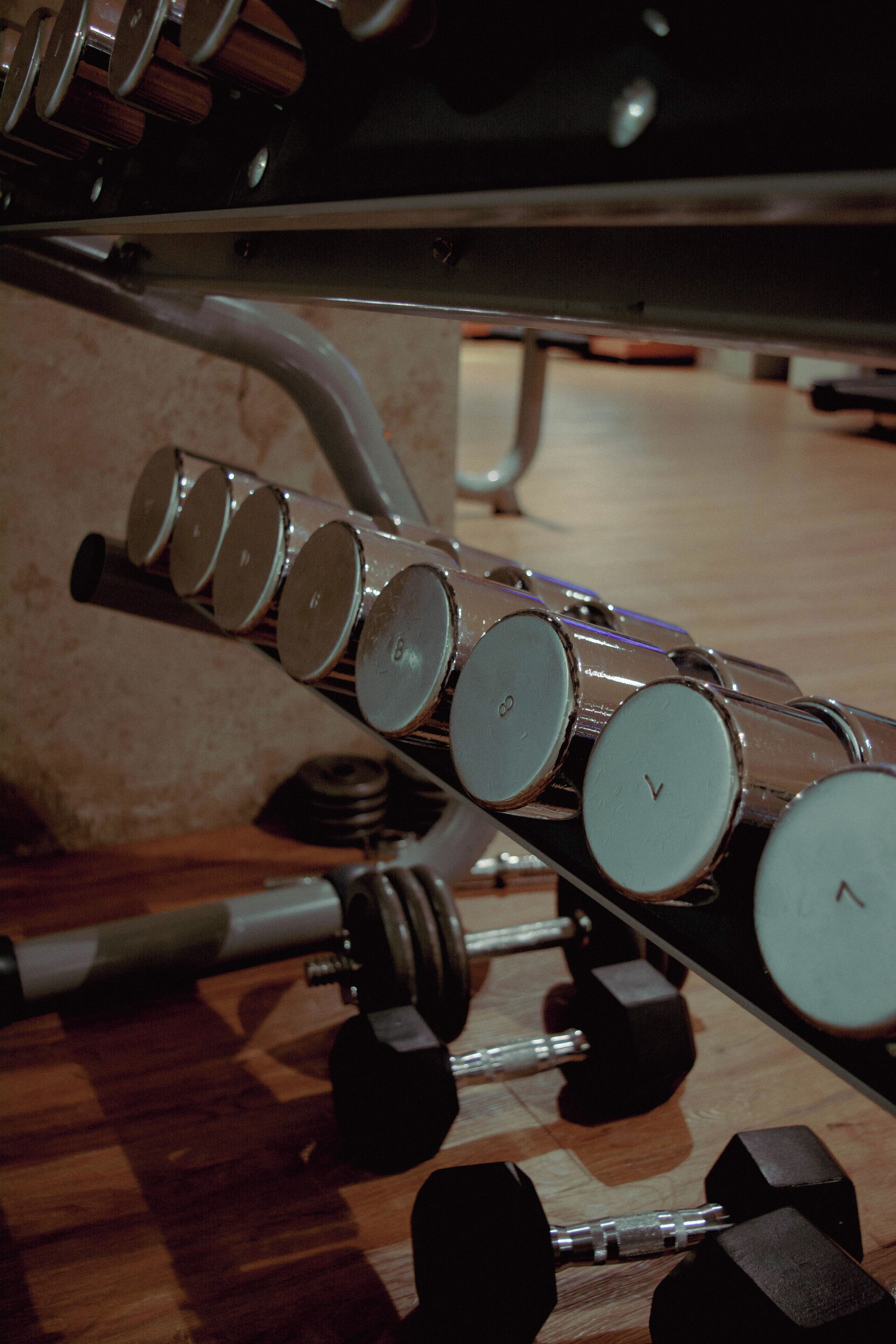 A gym with a variety of exercise equipment including dumbbells and a rowing machine.
