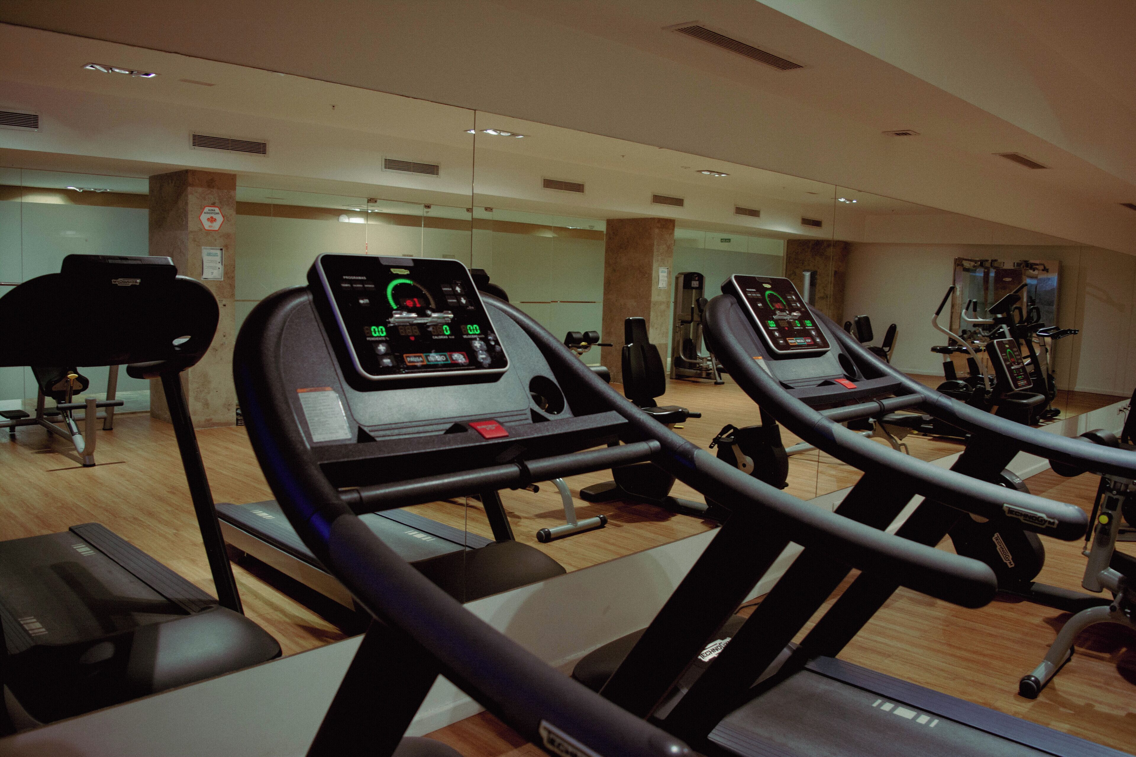 Un gimnasio con cintas de correr, bicicletas estáticas y máquinas de pesas.