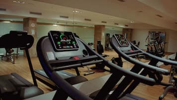 Un gimnasio con cintas de correr, bicicletas estáticas y máquinas de pesas.