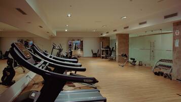 Un gimnasio con cintas de correr, bicicletas estáticas y pesas libres.