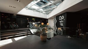 A modern interior with a skylight, a staircase, and a store named "OPTA". - Opta Coliving (Montevideo)