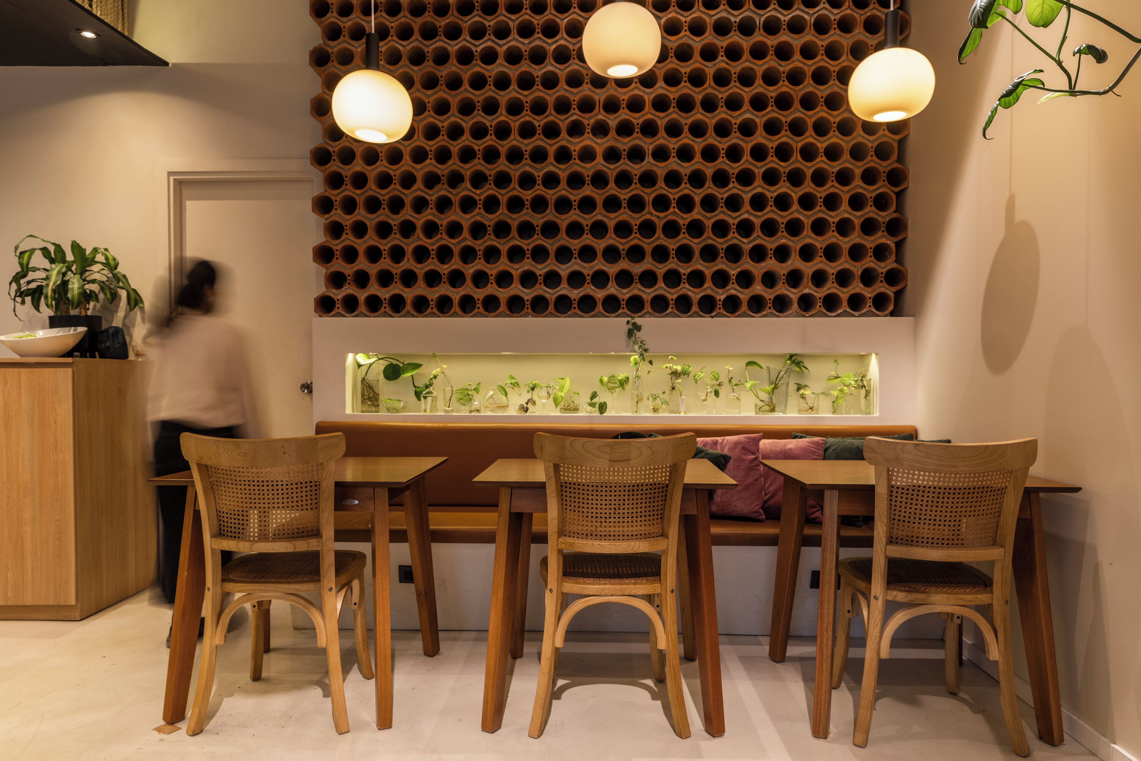 A dining area with a wooden table and chairs, a decorative wall with circular patterns, and pendant lighting.