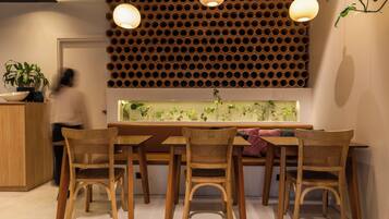 Un área de comedor con una mesa y sillas de madera, un muro decorativo con diseños circulares e iluminación colgante.