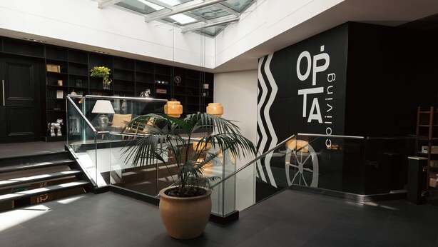 A modern interior with a glass ceiling, a staircase, and a wall with the text "OPTA". - Opta Coliving (Montevideo)