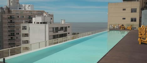 A rooftop pool with a view of the sea, surrounded by buildings.