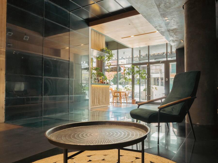 A modern interior with a round woven table, a green chair, and a glass partition.