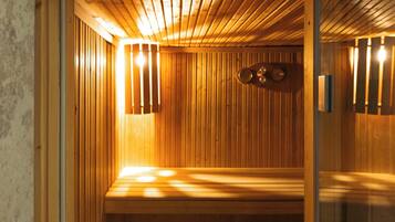 Una sauna con paredes y bancos de madera, una puerta de cristal y luces empotradas.