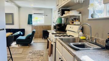 A modern kitchen with a gas stove, sink, and a dining area with a sofa and chairs.