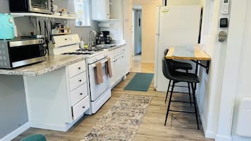 A kitchen with white cabinets, a microwave, stove, and a refrigerator.