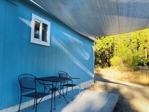 A blue building with a covered patio, a window, and a table with chairs. - Dafna, Unit 4 - One Bedroom, Cozy Little Home (Cromberg)