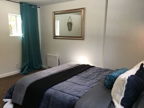 A bedroom with a bed, a window with curtains, a wall-mounted mirror, and a radiator. - Dafna, Unit 4 - One Bedroom, Cozy Little Home (Cromberg)