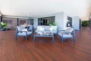 A modern outdoor living area with a wooden deck, a sofa set, and a dining table.