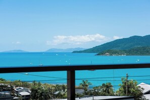 A coastal view with boats on the water, a clear sky, and a hilly landscape in the distance. - Airlie Oasis (Airlie)