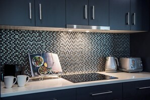 Una cocina moderna con gabinetes oscuros, un salpicadero estampado y una placa de inducción integrada.