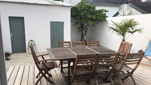 A wooden deck with a table and chairs, surrounded by a white building with a satellite dish. - HOUSE VILLA (Batz-sur-Mer)