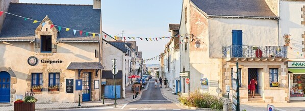 A narrow street lined with buildings, including a pharmacy and a creperie. - HOUSE VILLA (Batz-sur-Mer)