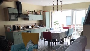 A cozy living room with a sofa, a dining table, and a kitchen area. - HOUSE VILLA (Batz-sur-Mer)
